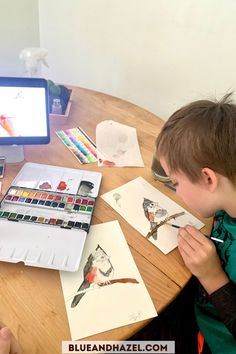 a young boy sitting at a table with some watercolors