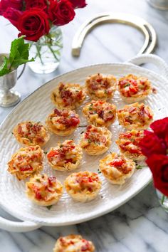 small appetizers on a white plate with red roses