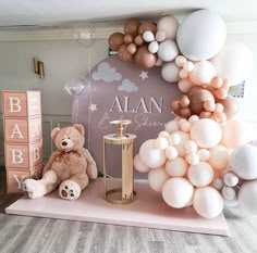 a teddy bear sitting on top of a table next to balloons and other items in front of it