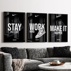 two black and white posters hanging on the wall above a gray couch in a living room