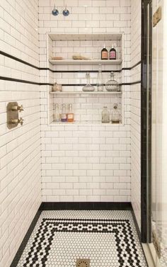 a white tiled bathroom with black and white floor tiles on the walls, shelving above the shower