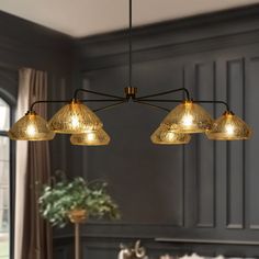 a chandelier hanging from the ceiling in a living room with grey walls and furniture