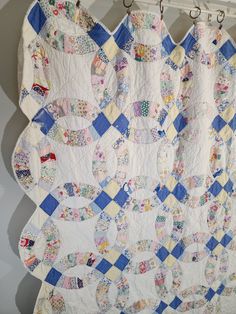 a quilt hanging from a hook in a room with white walls and blue checkered fabric