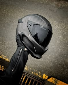 a motorcycle helmet sitting on the side of a road next to a black jacket and glove