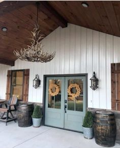 the front door of a building with two wooden barrels and a chandelier hanging from it's ceiling