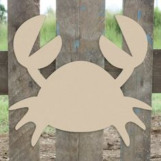 a crab cut out on the side of a wooden fence with grass in the background