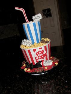 a birthday cake made to look like popcorn buckets with straws and candy on top