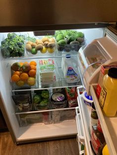 an open refrigerator filled with lots of fresh fruit and veggies, including oranges