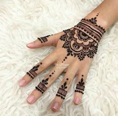 a woman's hand with henna tattoos on it and her hands painted black