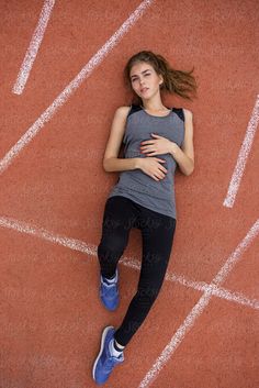 a young woman laying on the side of a track with her arms around her chest