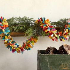 two pine cones sitting on top of a wooden box next to a christmas tree branch