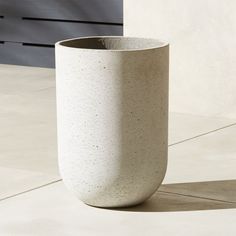 a white vase sitting on top of a cement floor