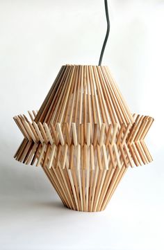 a vase made out of bamboo sticks on a white surface with a black cord attached to it