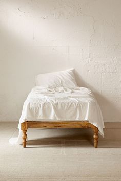 an unmade bed with white sheets and pillows