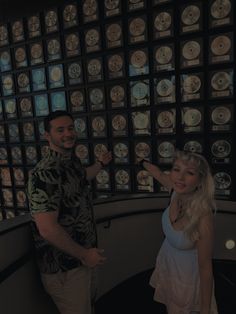 a man and woman standing in front of a wall full of cds with their hands up