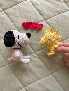 two crocheted stuffed animals sitting on top of a white bed next to each other