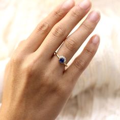 a woman's hand with a ring on it and a blue stone in the middle