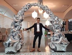 a man standing in front of a large metal arch with silver decorations on it's sides