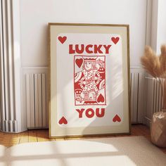 an art print with the words lucky you in red on it next to a potted plant