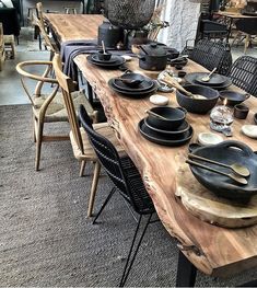 a wooden table topped with lots of black plates and bowls sitting on top of it