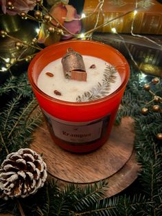 a candle that is sitting on a table next to some pine cones and christmas decorations