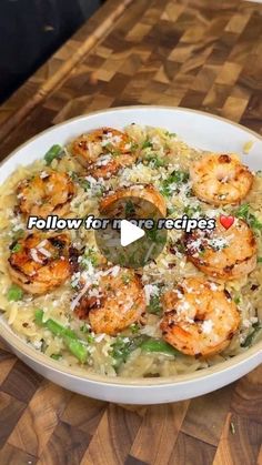 a white bowl filled with pasta and shrimp on top of a wooden table next to a knife