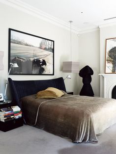 a bed sitting in a bedroom next to a fire place and a painting on the wall