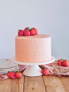 there is a cake with strawberries on top and pink napkins next to it