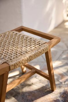 a wicker chair sitting on top of a stone floor next to a white wall