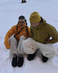 two people sitting in the snow with skis on