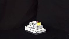 a lit candle sitting on top of a block of white paper in front of a black background