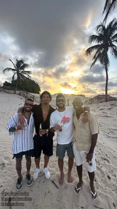 three men are standing on the beach with their arms around each other