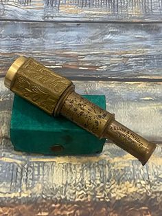 an antique brass telescope sitting on top of a green box with writing on the side