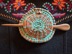 a close up of a woven object with a wooden spoon in the middle on a black surface