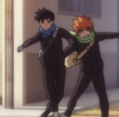 two young men in black suits and scarfs standing next to each other on the street