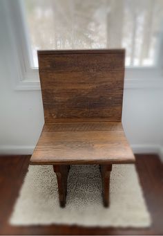 a wooden chair sitting on top of a white rug in front of a windowsill