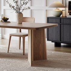 a dining room table with two chairs and a vase on the table next to it