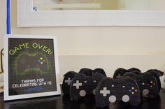 there are four black video game controllers on the table next to a sign that says game over