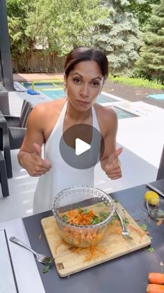 a woman is giving the thumbs up with her bowl of food in front of her