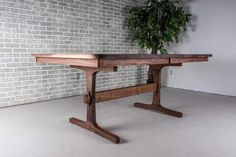 a wooden table sitting in front of a brick wall next to a potted plant