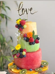 a multi - layered cake decorated with fruit and the word love is displayed on top