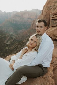 a man and woman sitting on top of a mountain