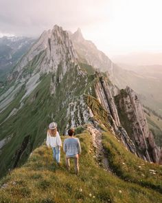 two people walking up the side of a mountain