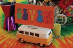 an orange and white vw camper van sitting on top of a colorful table cloth