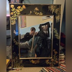 a man taking a selfie in front of a mirror with flowers and butterflies on it