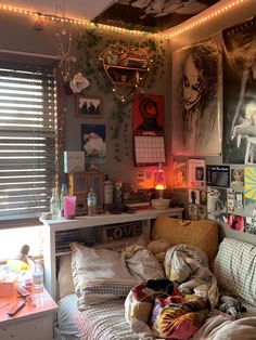 a messy bedroom with posters on the wall and lights strung from the ceiling above it