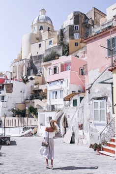 a woman is walking down the street in front of some buildings with balconies