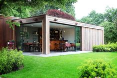 a garden room with sliding glass doors on the front and side walls, surrounded by lush green grass