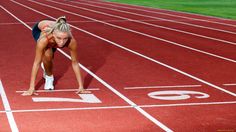 a woman is bent over on a running track