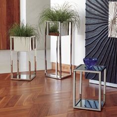 three vases with plants in them sitting on the floor next to eachother